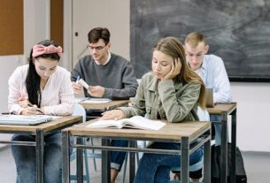 A group of teenagers focusing on studies in a classroom with a blackboard.
