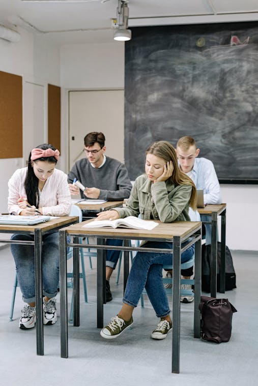 A group of teenagers focusing on studies in a classroom with a blackboard.